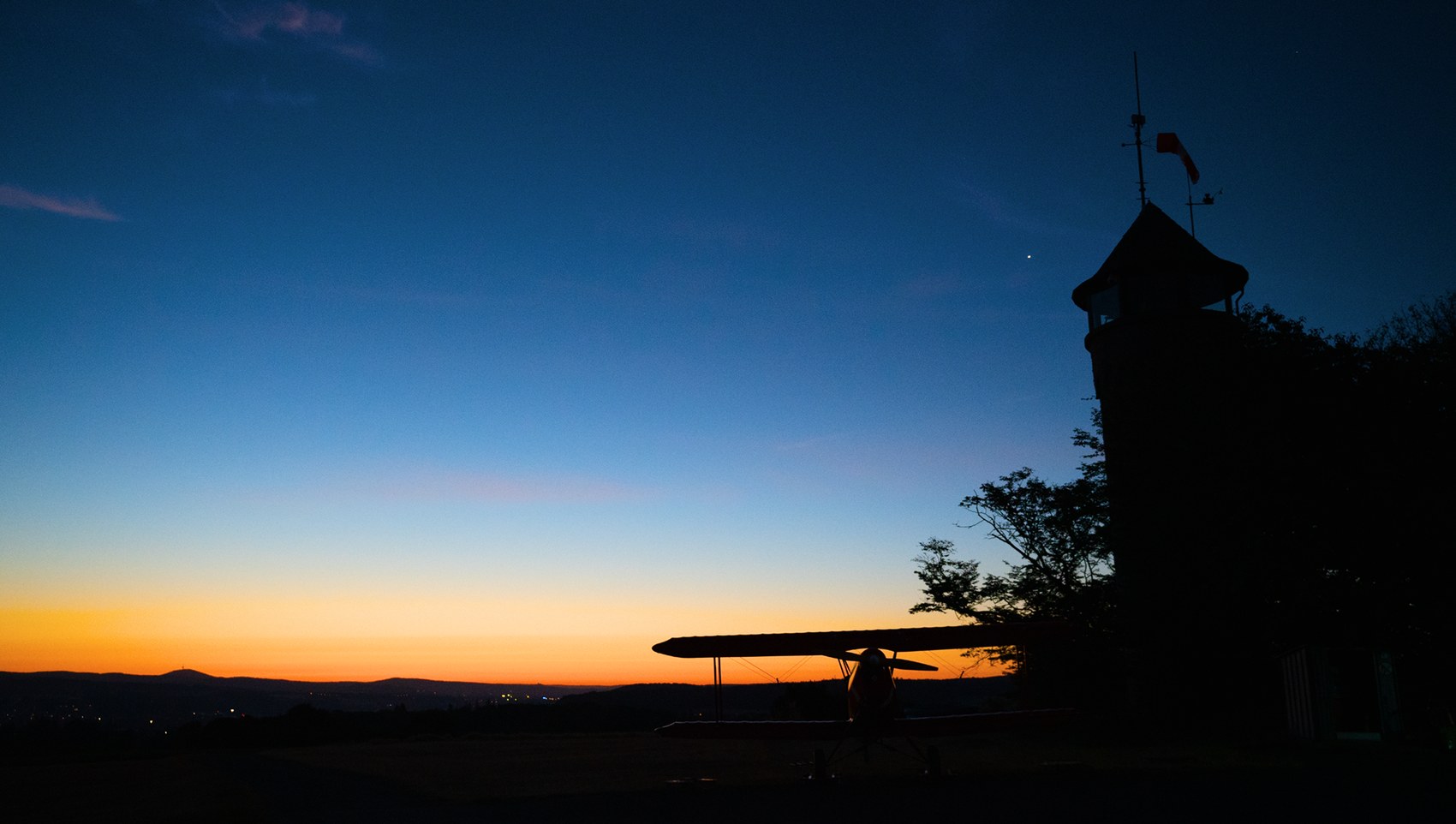 Segelflugzeug und Turm als Silhouetten in der blauen Stunde